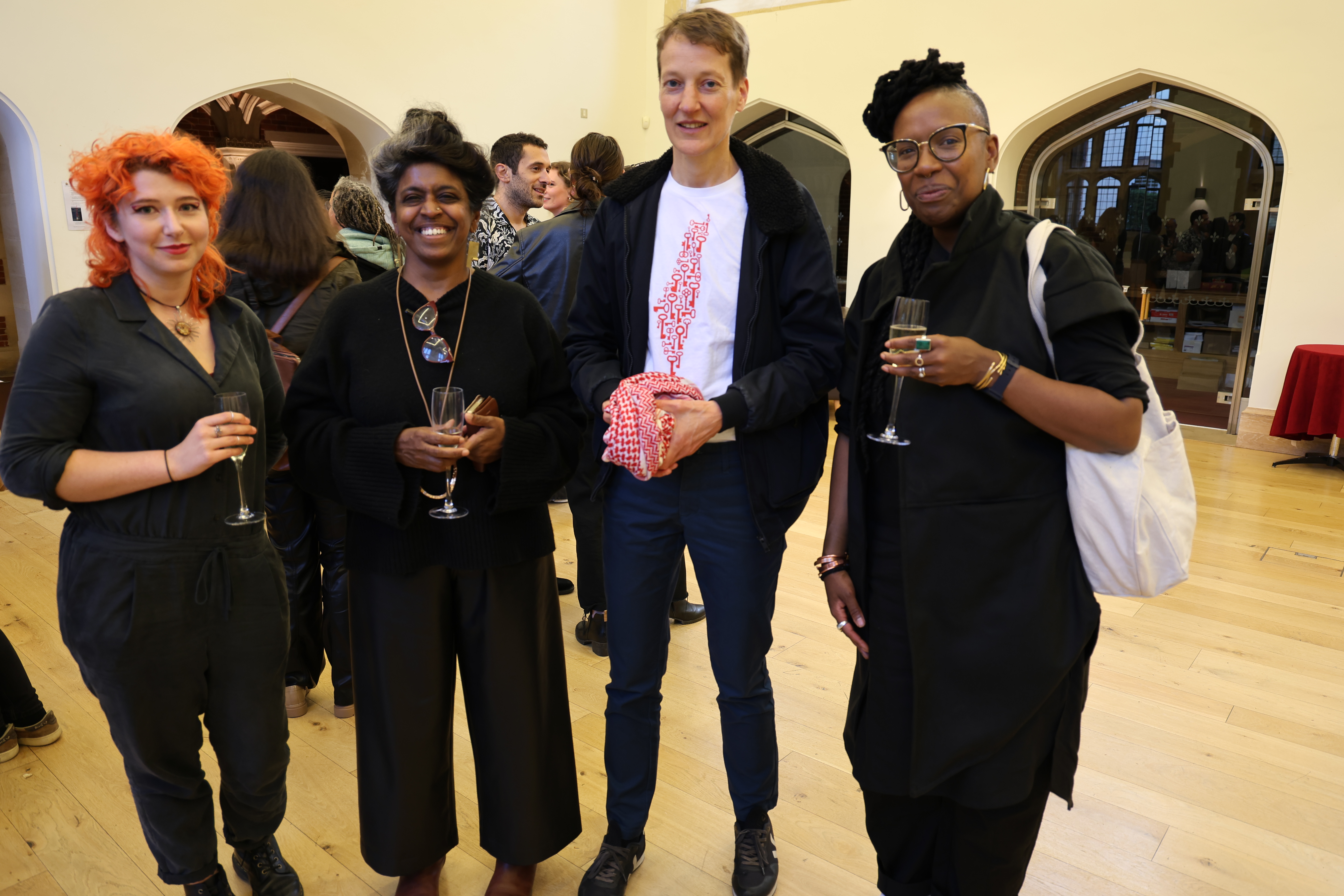 A group of four people in the reception hall of the Divinity School in St John's College, Cambridge, at the Alfred Dubs Lecture reception. The group includes the speaker, Professor Tendayi Achiume, furthest right, Professor Vasuki Nesiah second from left.