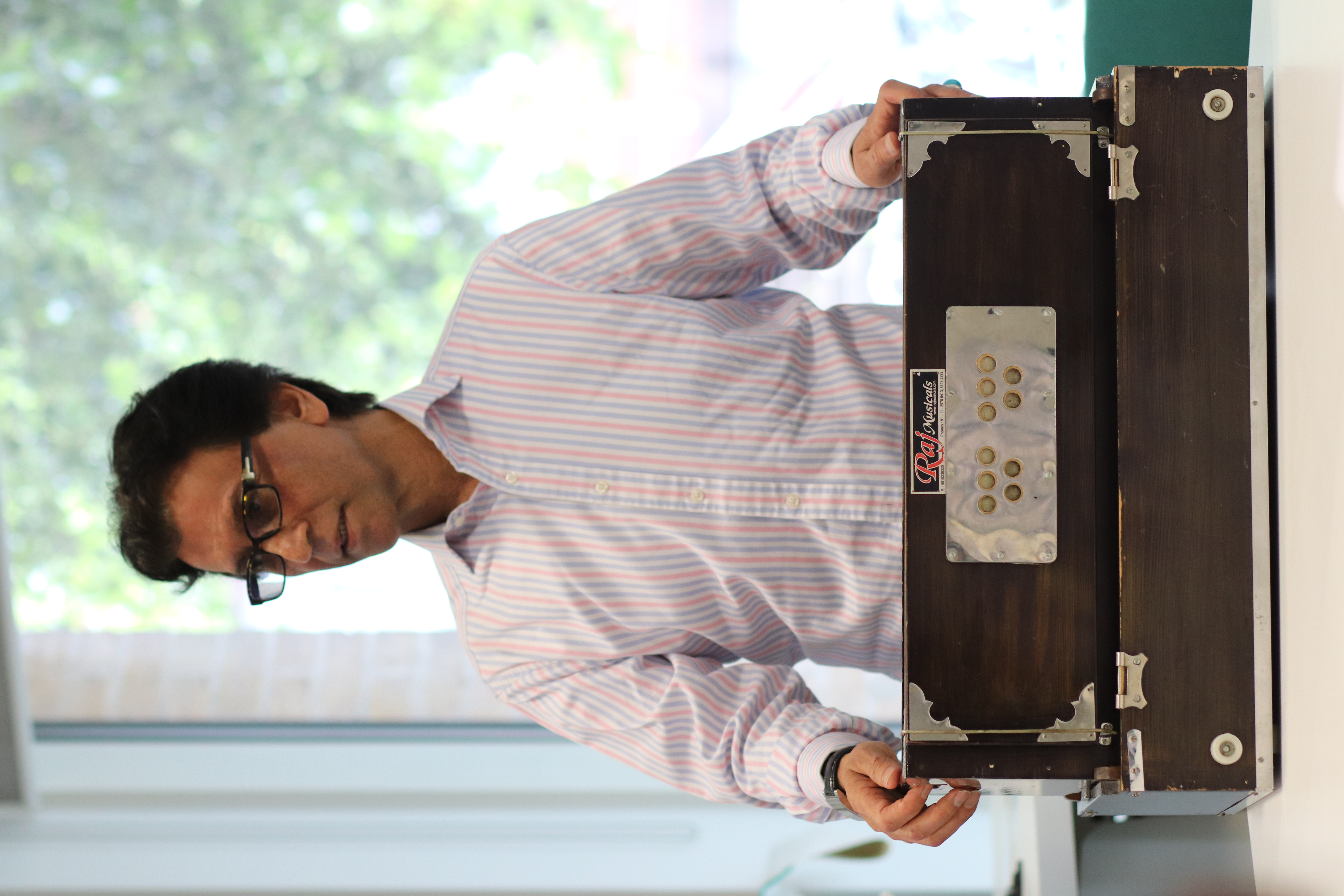 Mirwaiss Sidiqi, former country director of the Aga Khan Music Programme in Afghanistan, demonstrating how to play a harmonium at the Cambridge Refugee Week Community Arts Festival, on 22 June 2024.