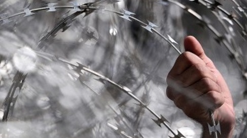 A refugee grabs onto the razor wire at the closed Greek – F.Y.R.O.M. border crossing, March 2016 Image: Louisa Gouliamaki