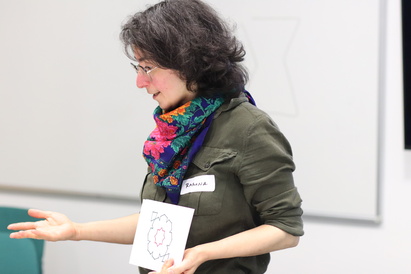 Ramona Zadissa, Iranian-born artist, holding an image of a geometric pattern commonly found in Islamic ceramics and textiles, as a demonstration of how it is created. Photograph taken at the Cambridge Refugee Week Community Arts Festival, on 22 June 2024.