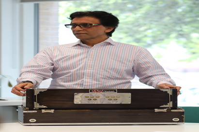 Mirwaiss Sidiqi, former country director of the Aga Khan Music Programme in Afghanistan, demonstrating how to play a harmonium at the Cambridge Refugee Week Community Arts Festival, on 22 June 2024.